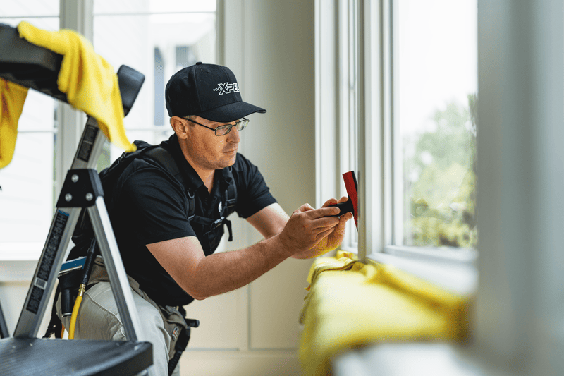 XPEL installer applying window film to residential glass