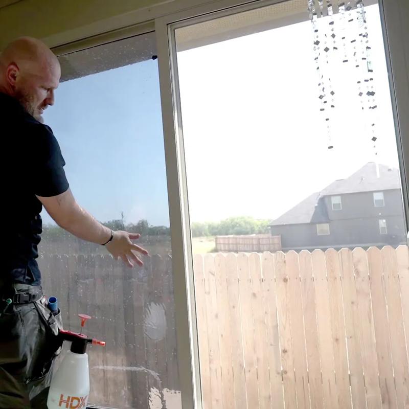 man installing window tints on a home