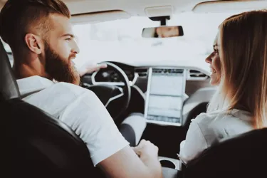 Man Is Driving A Tesla Car. Girl At Front Seat.